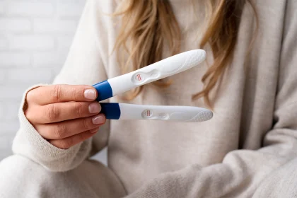 Pozitif hamilelik test sonuçlarını gösteren iki test çubuğunu tutan kadın eli. hamilelik belirtileri